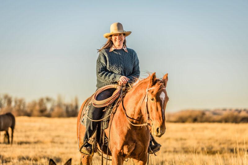 Rachel Larsen smiling while on horseback at sunset